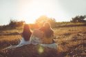 Three young women sitting in field and enjoying the sunset