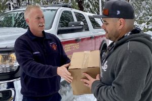 Ebbetts Pass Fire Protection Chief Mike Johnson delivering an American Red Cross emergency food box to a family snowed in by this storm, Blue Lake Springs
